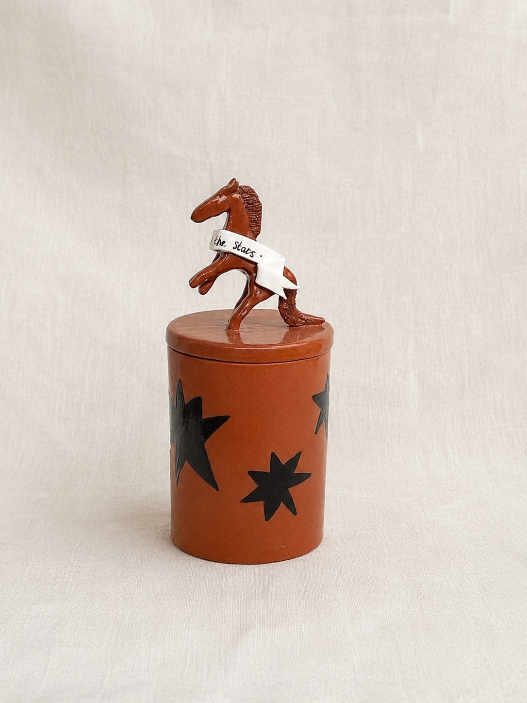 the horses are calling handmade ceramic lidded jar with star decorations and sculpted horse with ribbon on top of the lid